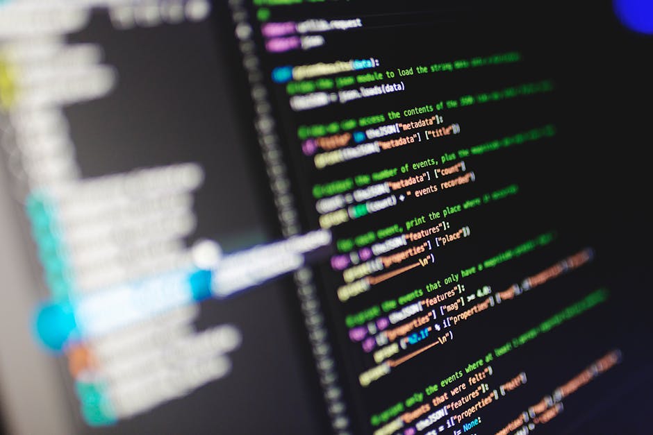 A close-up view of a computer screen displaying lines of colorful code with syntax highlighting in shades of green, purple, blue, orange, and white. The code is arranged in vertical lines with various